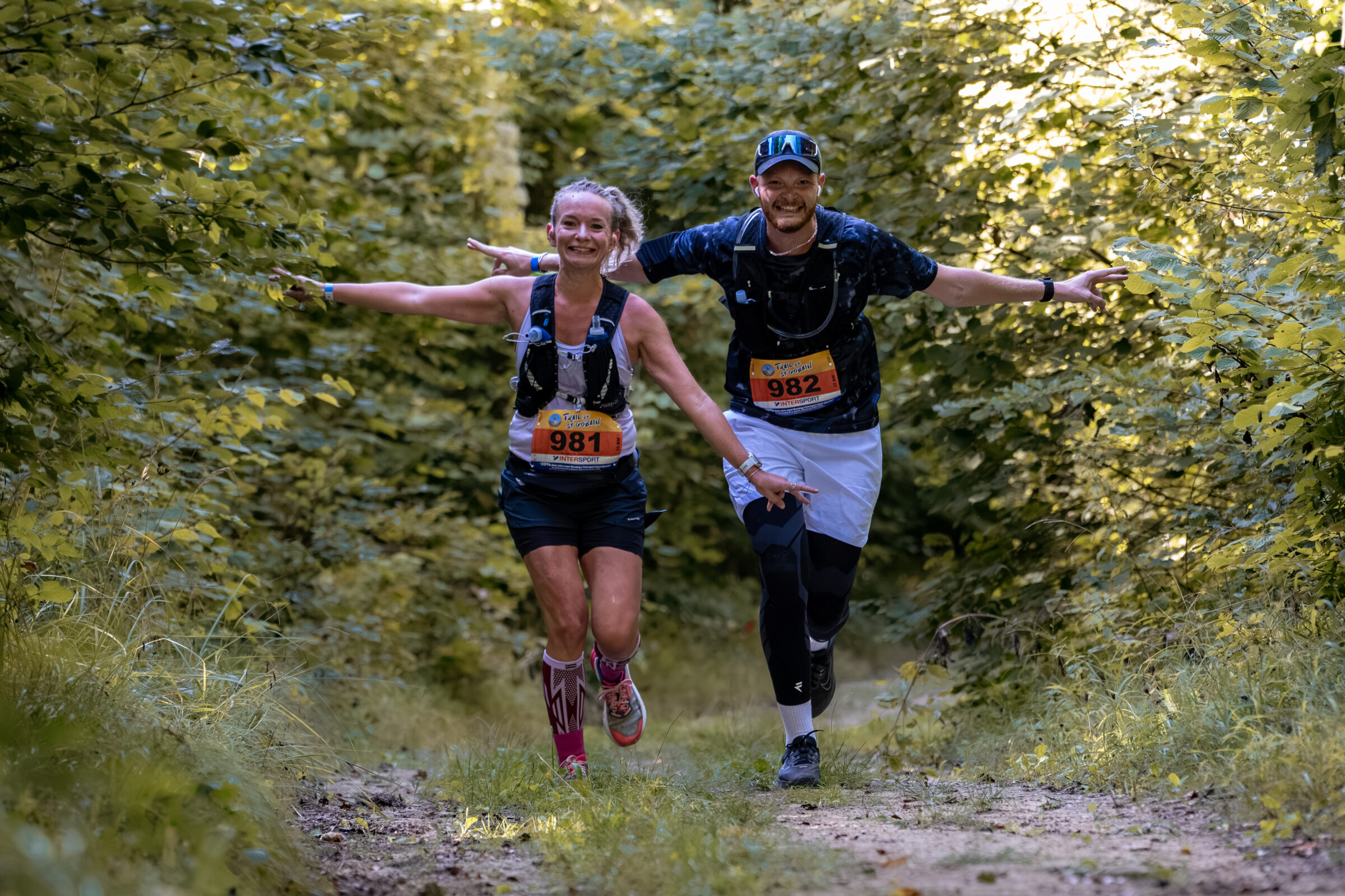 Deux coureurs avancent ensemble sur un sentier de la forêt de Saint-Gobain, au fil du parcours du Trail.